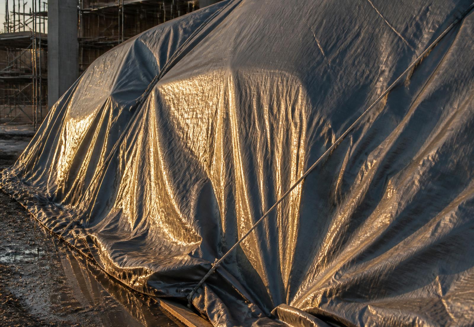 Heavy-duty tarpaulin sheet stretched against a stormy sky
